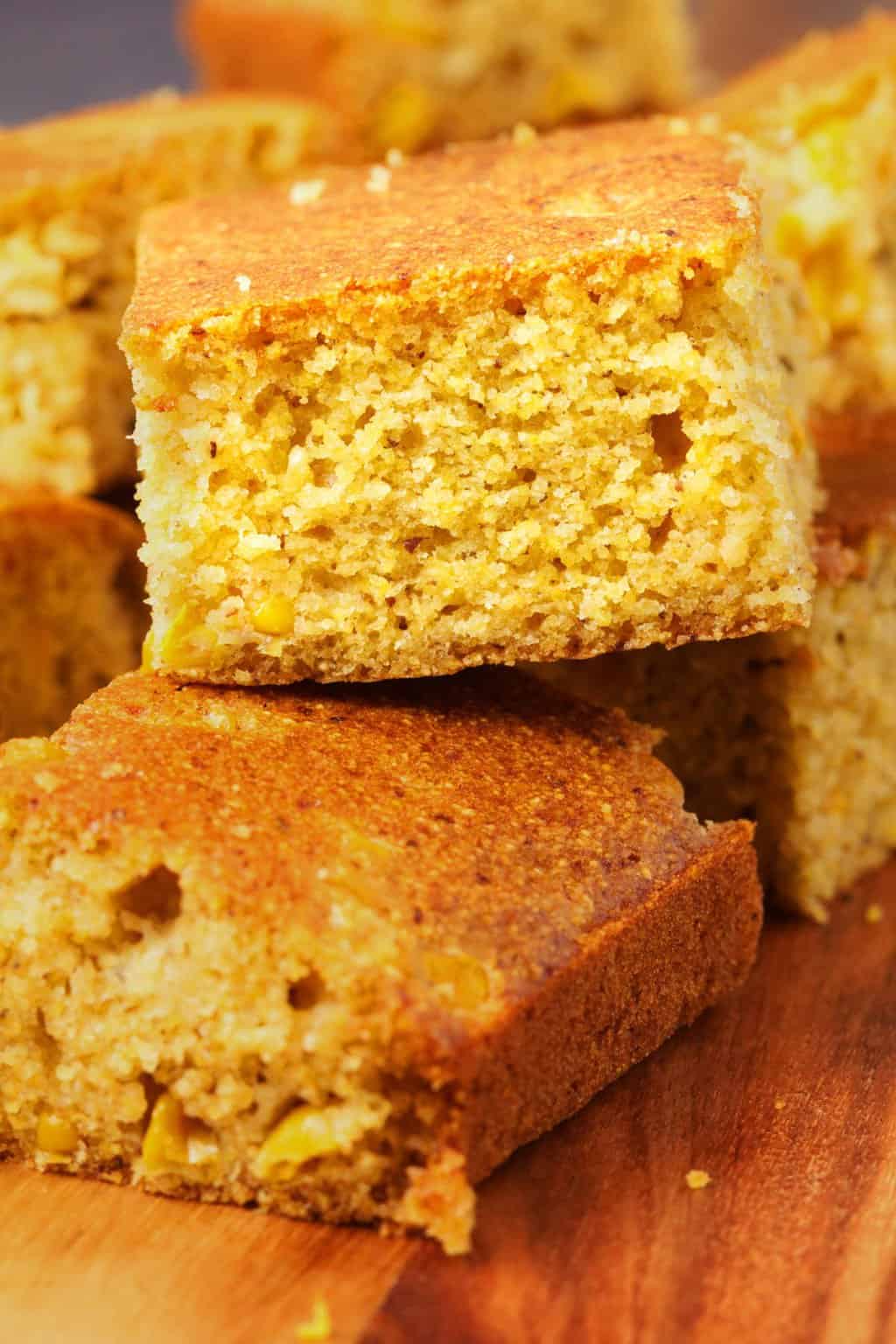 Golden square pieces of vegan cornbread on a rustic wooden board